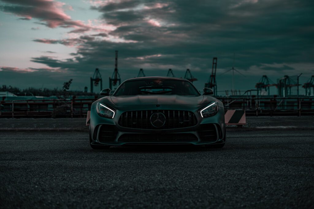 AMG Mercedes GTR parked beside production plant at dusk, retouched with Photoshop dodge & burn, gradient maps, and tonal adjustments for cinematic realism.
