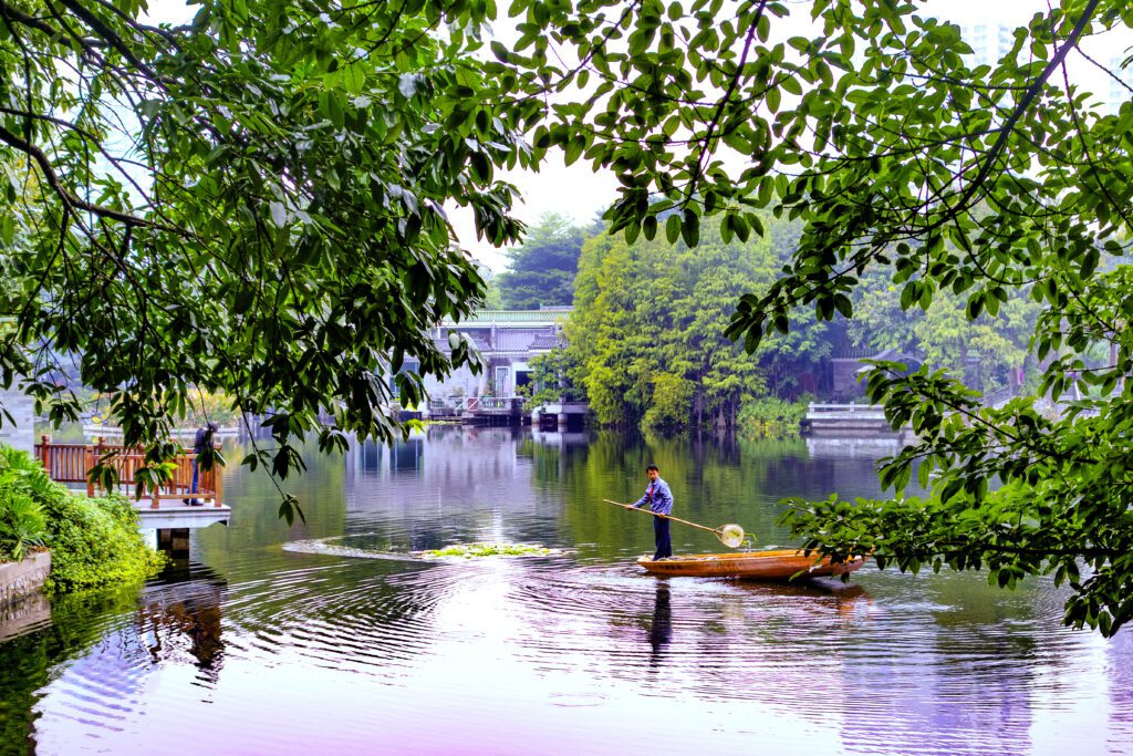 Man rowing a boat across a calm lake, retouched using dodge & burn and gradient maps for editorial motion and cinematic tonal depth.