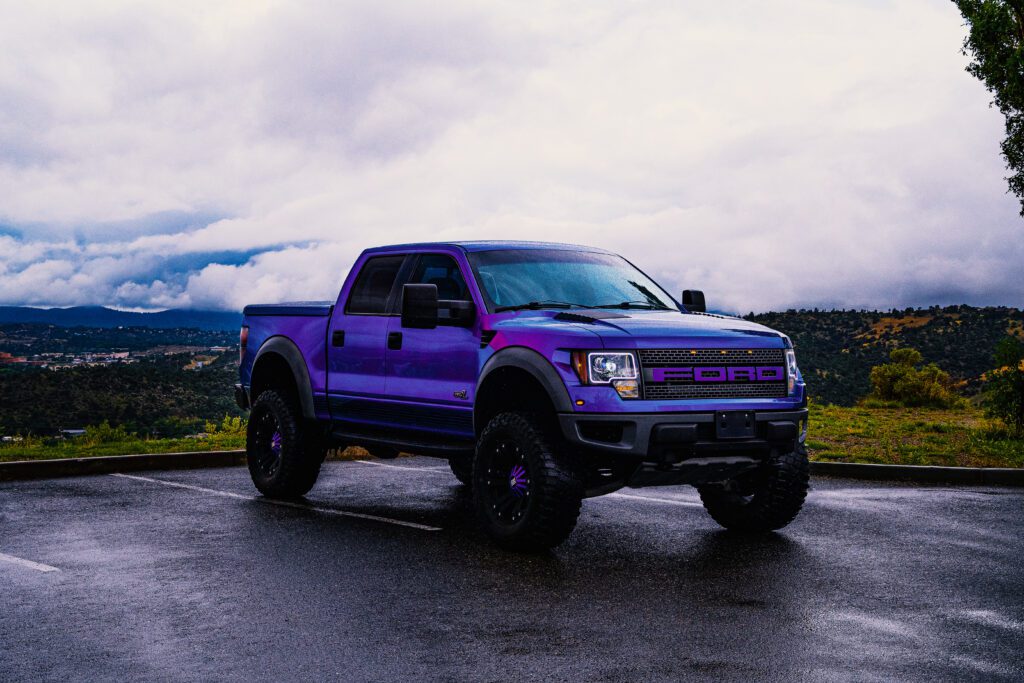 Purple Ford truck on a wet mountain road after rain, retouched with Photoshop gradient maps, dodge & burn, and tonal adjustments for cinematic realism.