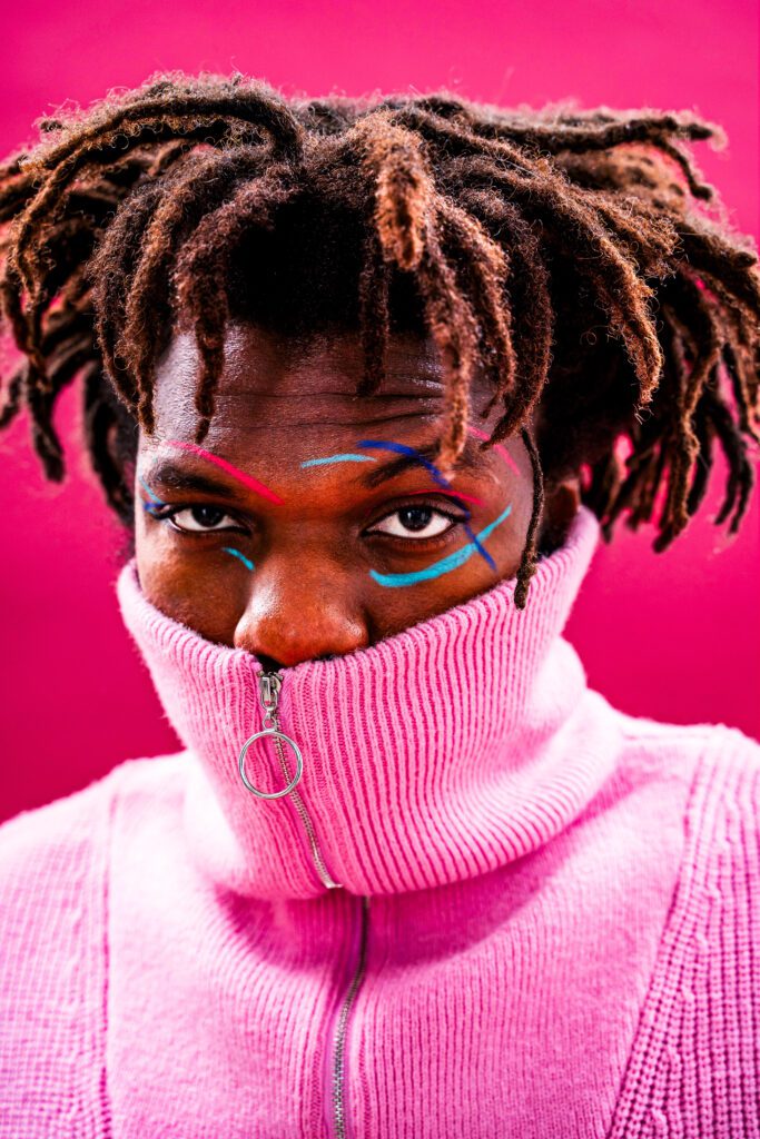 “Male fashion model in pink outfit, retouched with Photoshop dodge & burn, frequency separation, and cyber-luxe gradient maps for Gen-Z editorial clarity and visual impact.